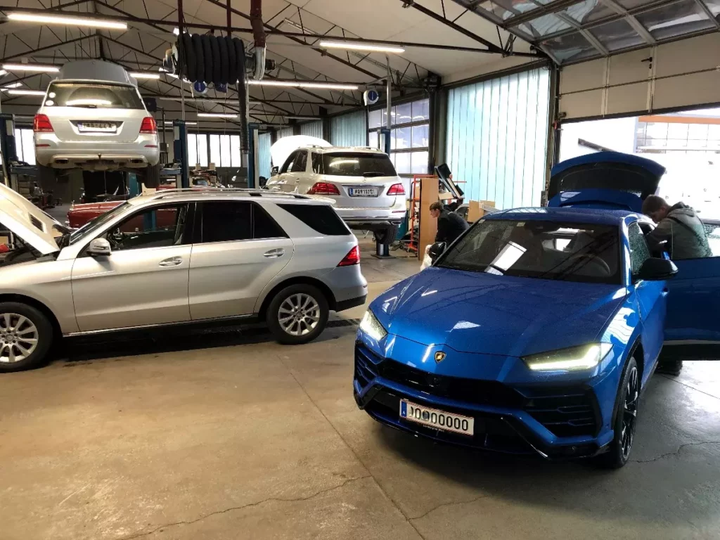 Autowerkstatt mit drei grauen Mercedes Geländewagen und einem blauen Lamborghini