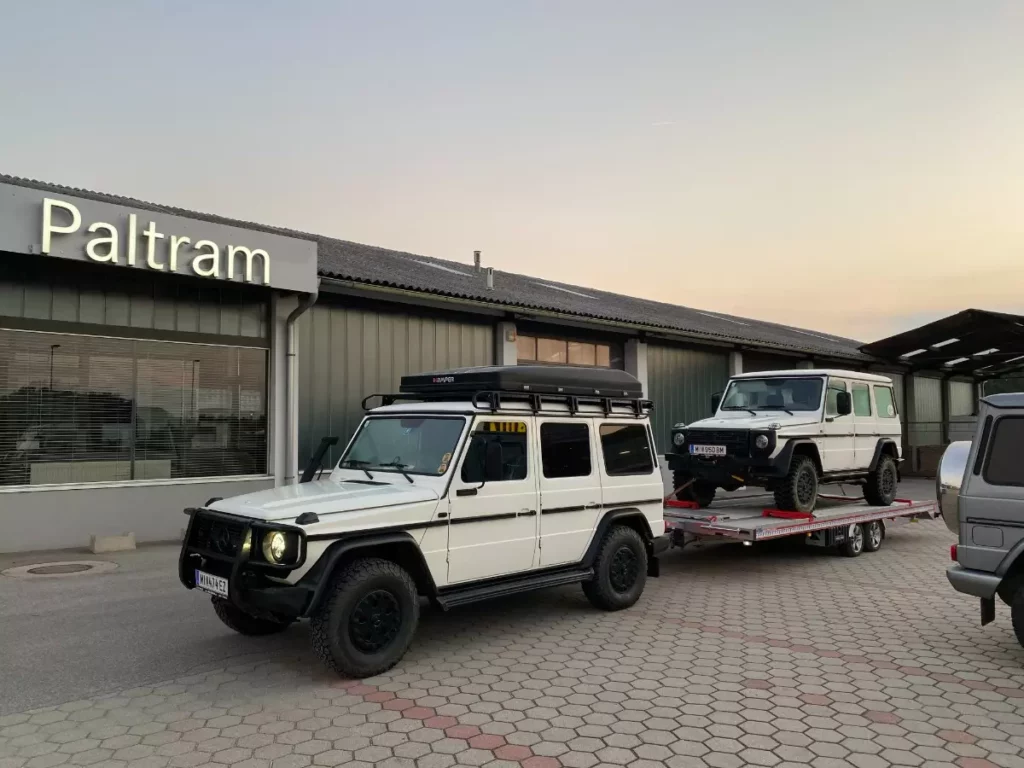 weißer Mercedes Geländewagen mit Autoanhänger schleppt einen Mercedes ab