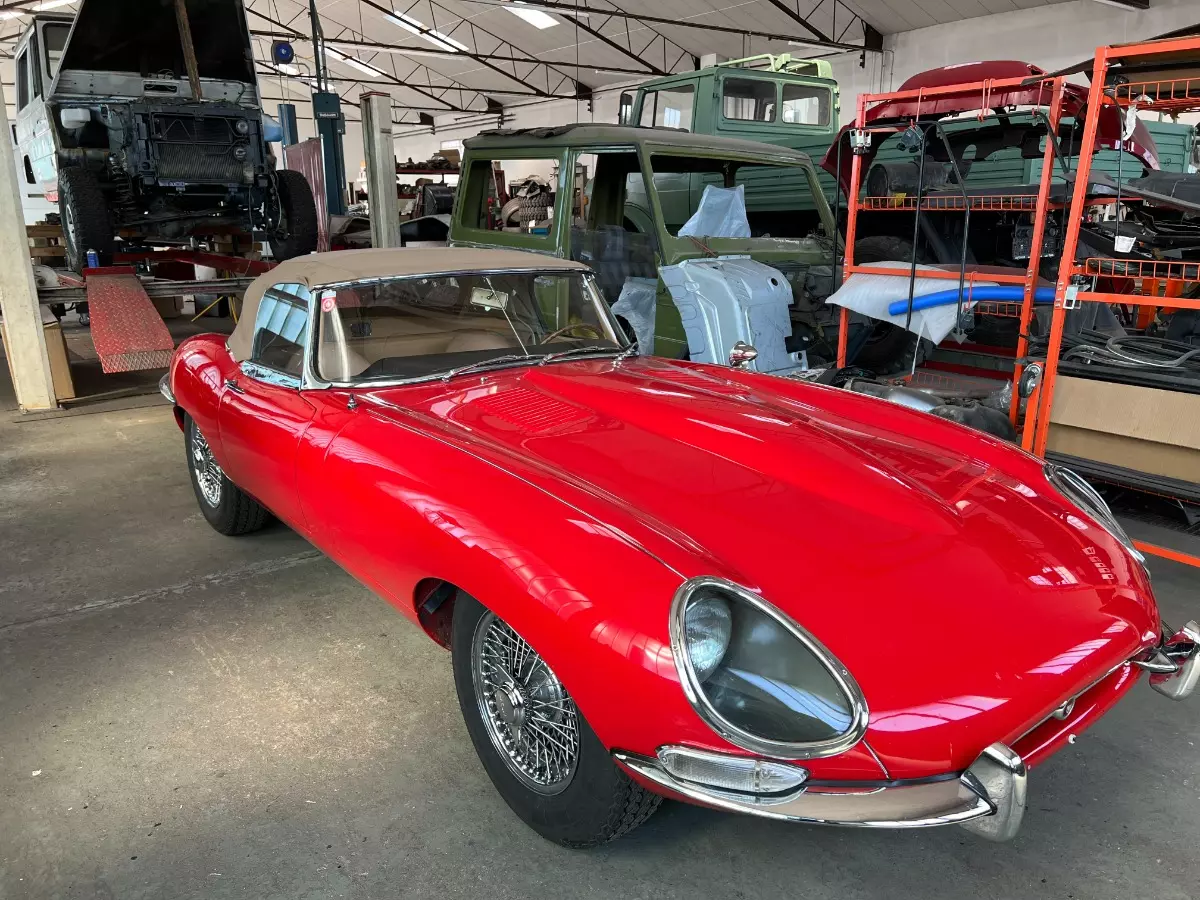 rotes Oldtimer Cabrio mit geschlossenem beigen Dach und langer Motorhaube